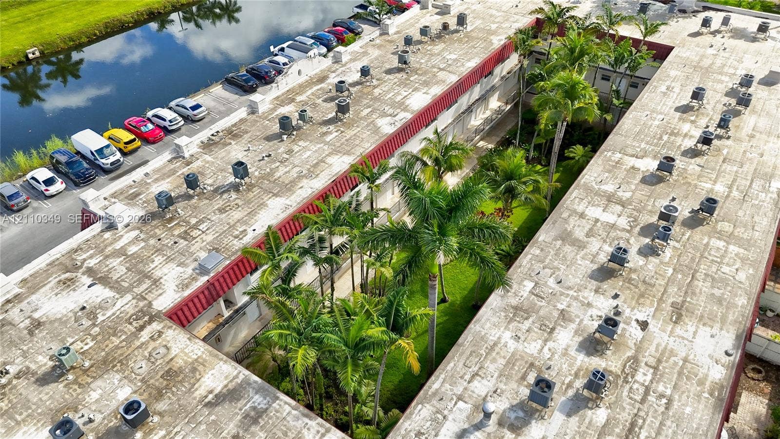 8600 SW 67th Avenue, #905, Pinecrest, Pinecrest, FL 33156 Aerial view featuring a multi-unit property with a central landscaped courtyard, mature palm trees, designated surface parking, and waterfront proximity