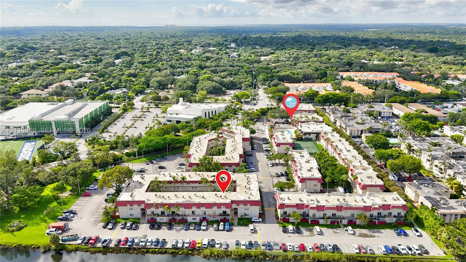 8600 SW 67th Avenue, #905, Pinecrest, Pinecrest, FL 33156 Aerial perspective of a multi-building residential complex featuring low-rise structures with red-tiled rooflines, shared courtyards, an outdoor swimming pool, and dedicated parking areas