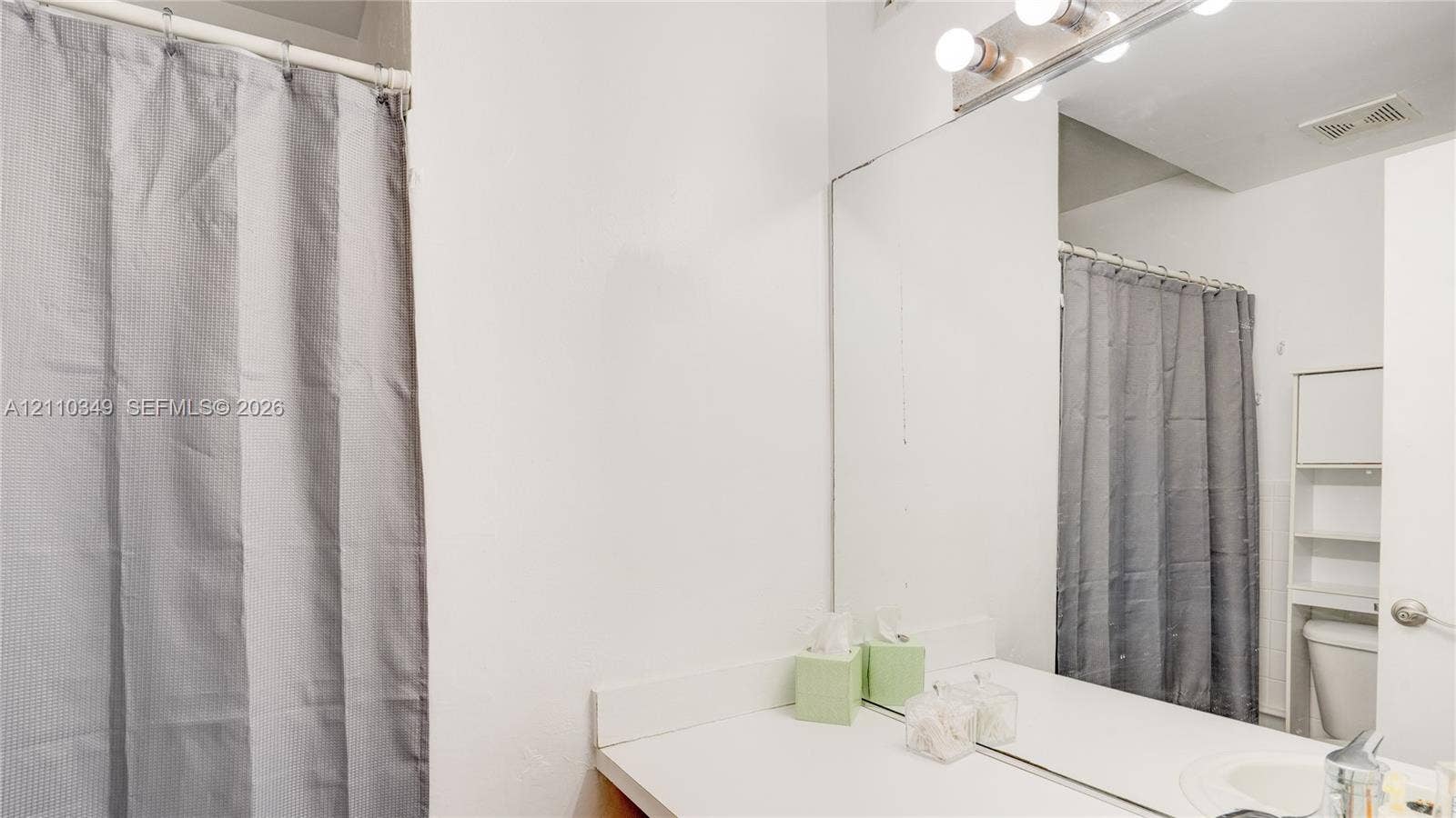 8600 SW 67th Avenue, #905, Pinecrest, Pinecrest, FL 33156 Bathroom featuring a full-width vanity mirror, a four-bulb vanity light fixture, and a built-in over-the-toilet storage unit
