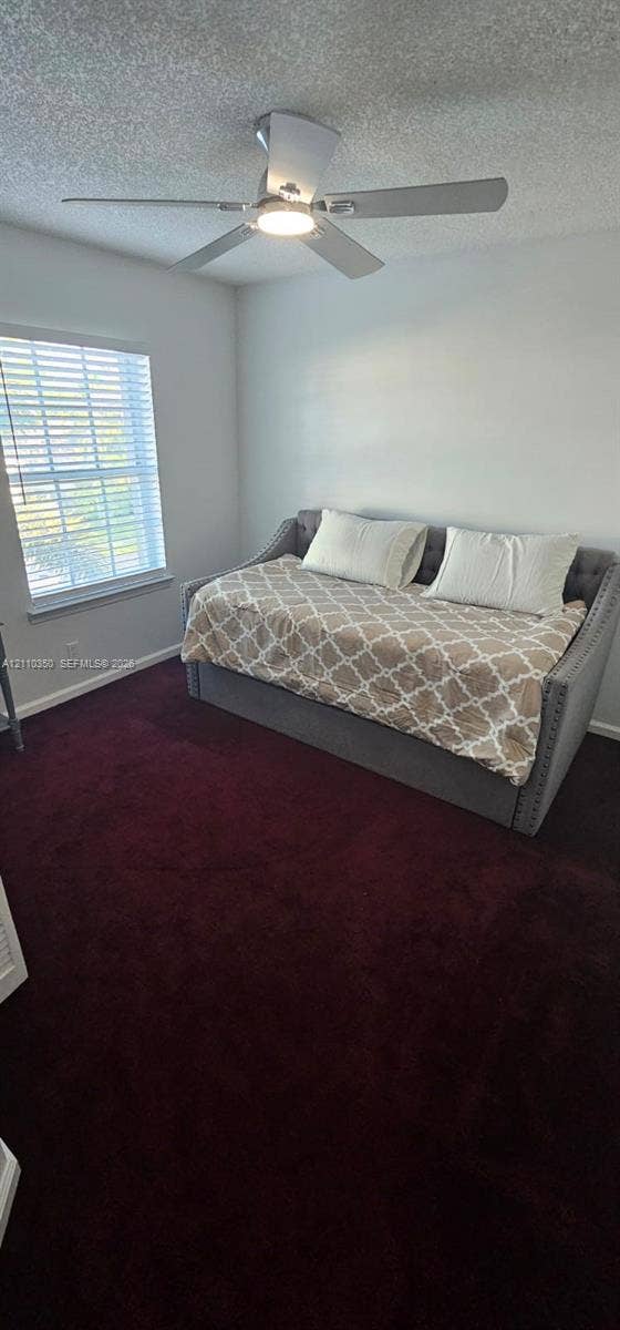 Room featuring deep-toned carpeting, white walls, and a ceiling fan with an integrated light fixture