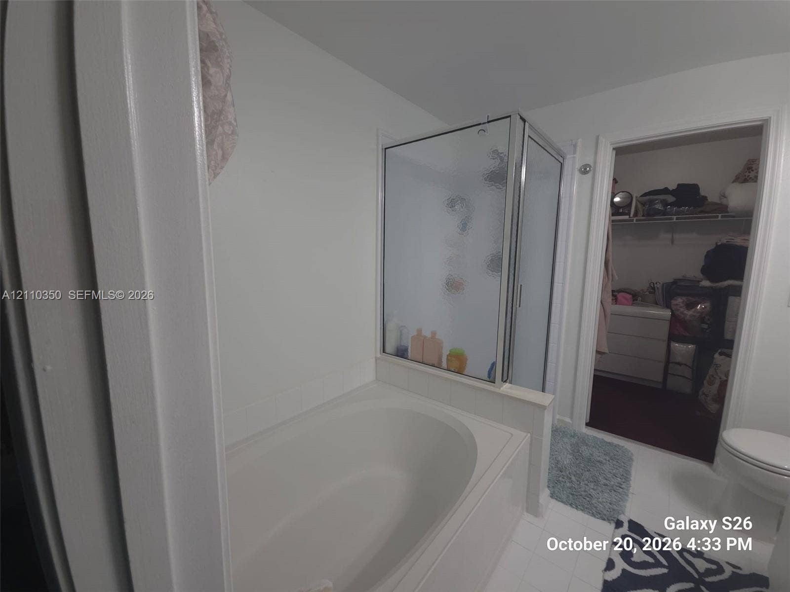 Oval soaking tub, corner glass-enclosed shower, and tiled flooring