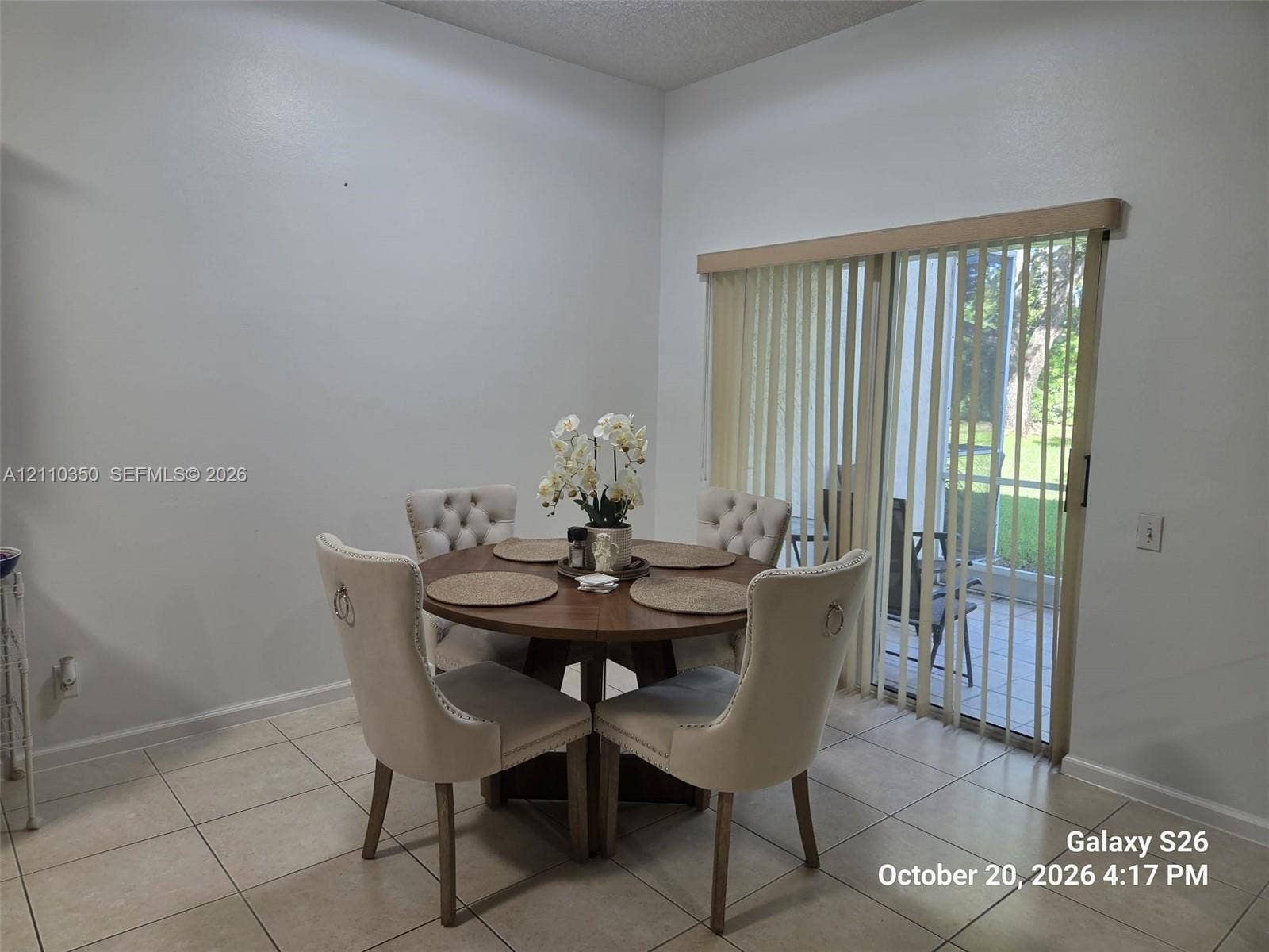 Neutral-toned ceramic tile flooring and sliding glass doors featuring vertical blinds