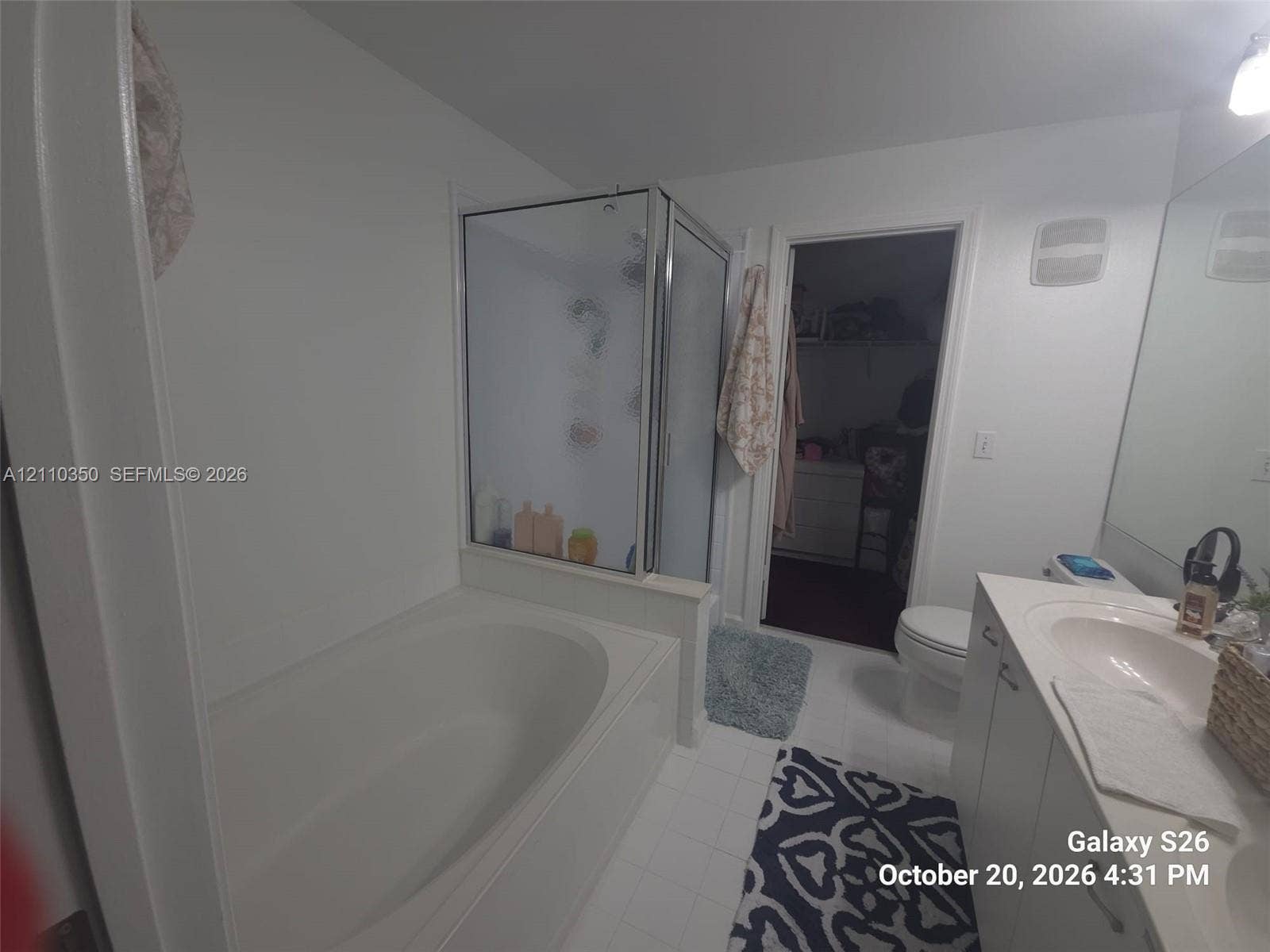 Bathroom featuring an oval soaking tub, separate glass-enclosed shower, integrated vanity with a molded sink, and wall-to-wall mirror