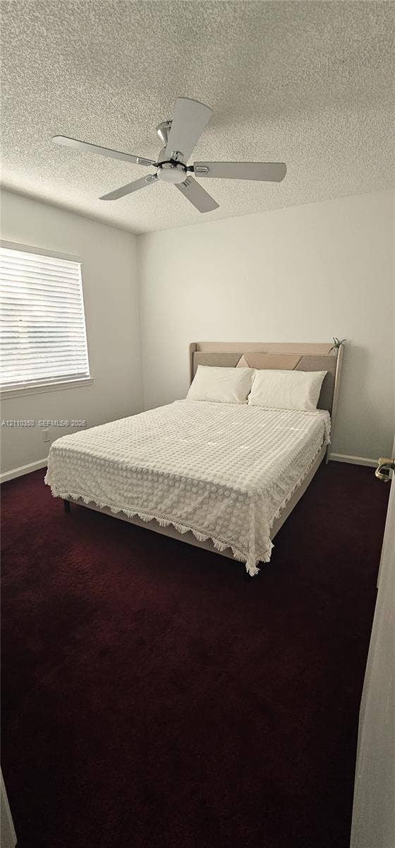 Room featuring deep-toned carpet flooring, a ceiling fan with integrated lighting, and a window with horizontal blinds