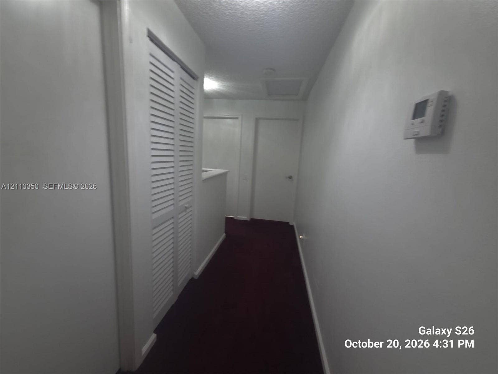 Interior hallway featuring louvered bi-fold closet doors, wall-mounted thermostat, and solid-core interior doors