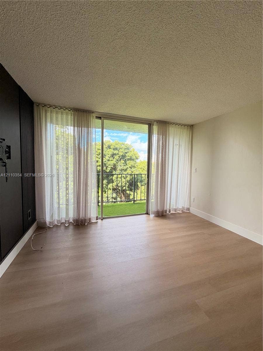 8801 W Flagler Street, #309, Miami, Miami, FL 33174 Wood-finish flooring, floor-to-ceiling sliding glass doors, and a private balcony featuring a metal railing