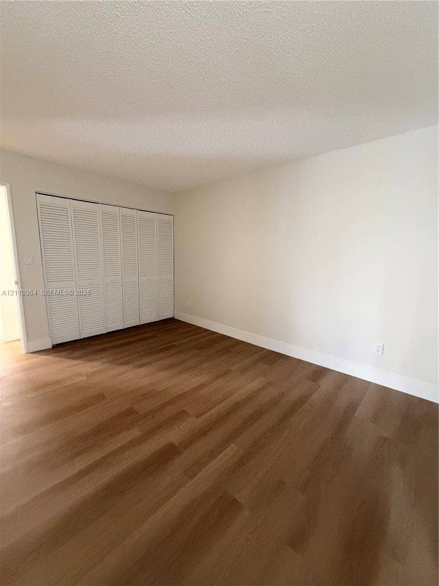 8801 W Flagler Street, #309, Miami, Miami, FL 33174 Room featuring wood-finish flooring, neutral walls, and a large reach-in closet with white louvered bi-fold doors