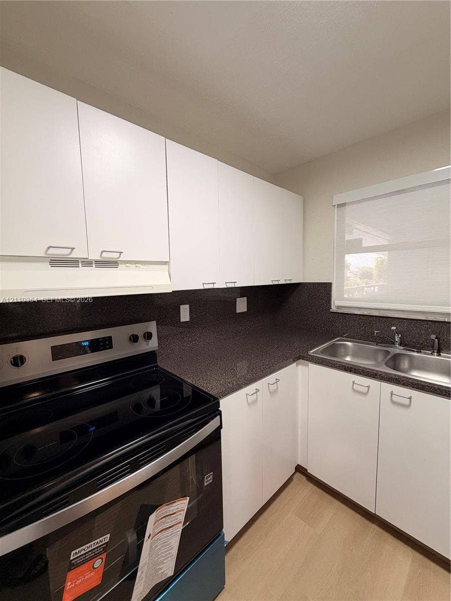 8801 W Flagler Street, #309, Miami, Miami, FL 33174 Kitchen featuring white flat-panel cabinetry, dark stone-finish countertops, stainless steel dual-basin sink, and integrated electric range