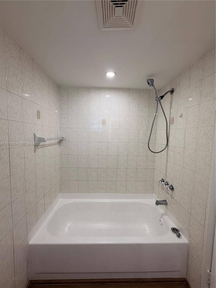 8801 W Flagler Street, #309, Miami, Miami, FL 33174 Alcove bathtub featuring white tile wall surround, chrome handheld shower fixture, integrated metal towel bar, and recessed lighting