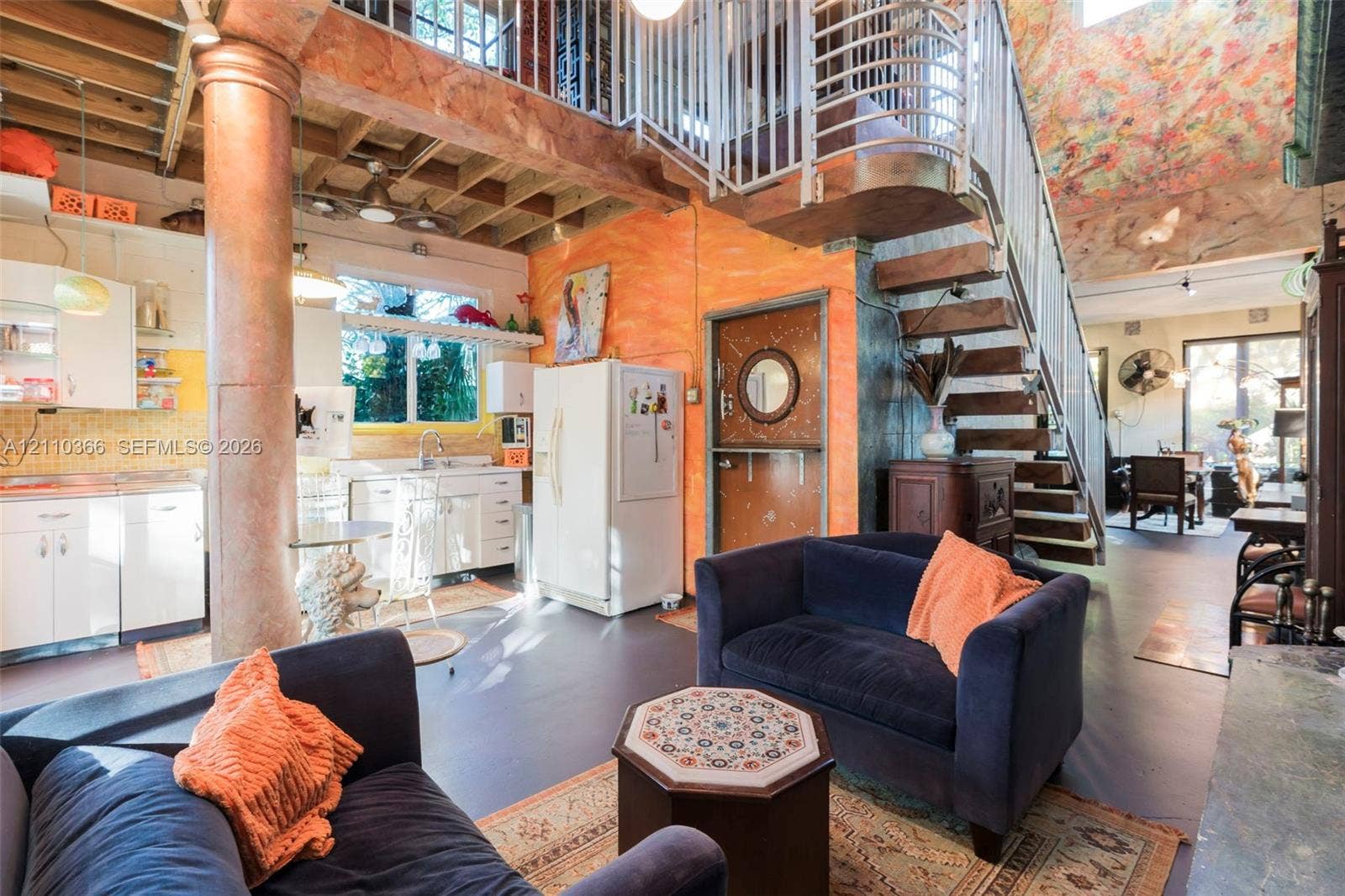 2361 SW 18th Avenue, Fort Lauderdale, FL 33315 Open-concept interior featuring a structural support column, exposed ceiling joists, a metal staircase with a matching railing, and a Dutch-style door with a circular window