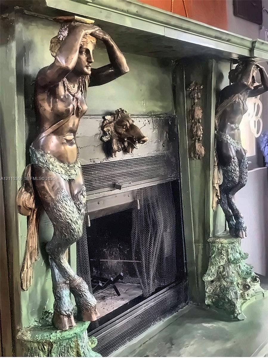 2361 SW 18th Avenue, Fort Lauderdale, FL 33315 Fireplace surround featuring dual metallic caryatid supports, ornate figural wood-finish detailing, and a central animal motif relief