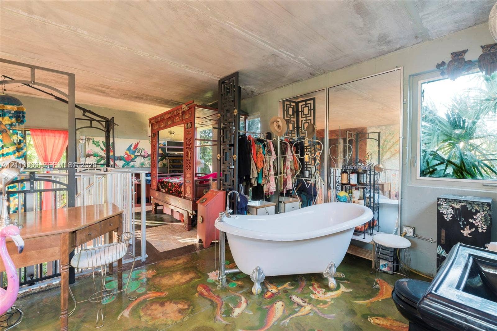 2361 SW 18th Avenue, Fort Lauderdale, FL 33315 Freestanding clawfoot soaking tub with a floor-mounted faucet, expansive mirrored wall panels, and stained concrete flooring with decorative artistic detailing