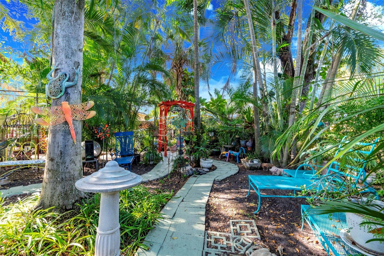 2361 SW 18th Avenue, Fort Lauderdale, FL 33315 Landscaped grounds featuring mature palm trees, a concrete paver walkway, and a decorative metal garden arch