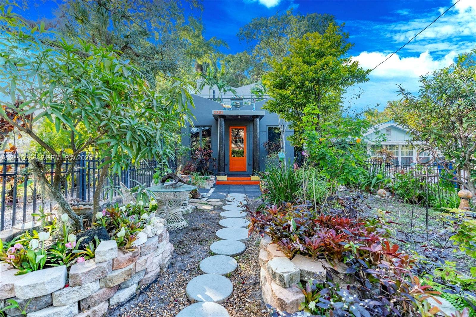 2361 SW 18th Avenue, Fort Lauderdale, FL 33315 Exterior facade featuring a bold orange front door, columns, flat roofline, stone-finished raised planter beds, and a circular paver walkway