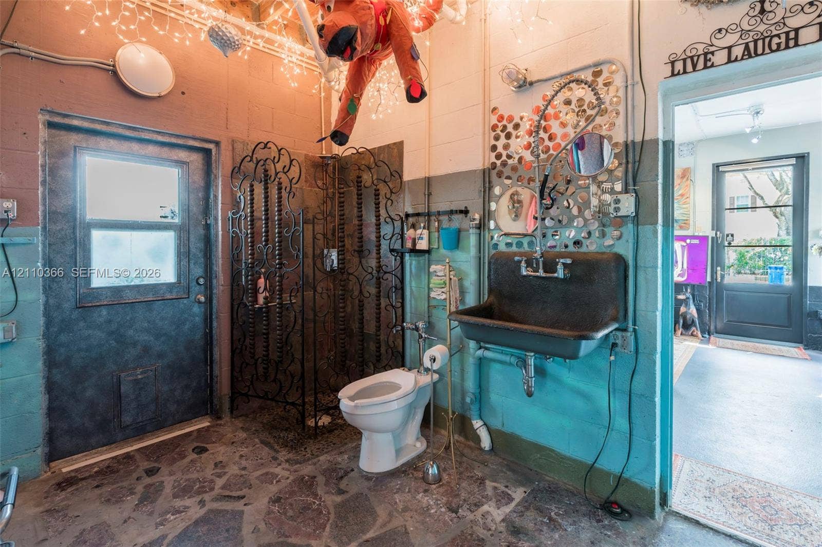 2361 SW 18th Avenue, Fort Lauderdale, FL 33315 Industrial-style space featuring a wall-mounted utility sink, metal-framed walk-in shower enclosure, floor-to-ceiling concrete block walls, and flagstone flooring