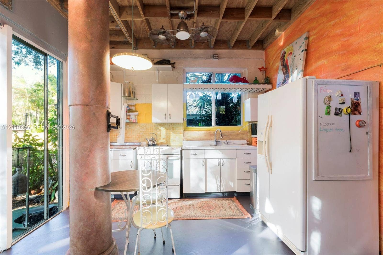 2361 SW 18th Avenue, Fort Lauderdale, FL 33315 Kitchen featuring white cabinetry, an exposed beam ceiling, a structural support column, and floor-to-ceiling glass sliding doors