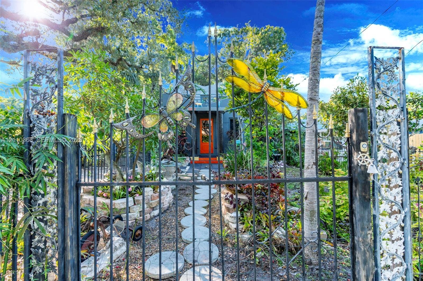 2361 SW 18th Avenue, Fort Lauderdale, FL 33315 Custom metal gate featuring integrated insect-themed art, stone-paver walkway, and stone-retaining wall garden beds