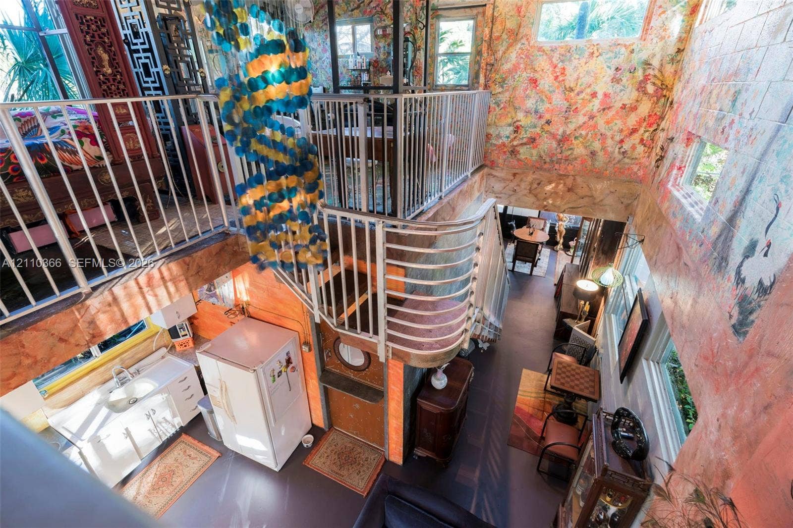 2361 SW 18th Avenue, Fort Lauderdale, FL 33315 Multi-level interior featuring a mezzanine with metal railings, a curved staircase, floor-to-ceiling mural walls, and multiple clerestory windows