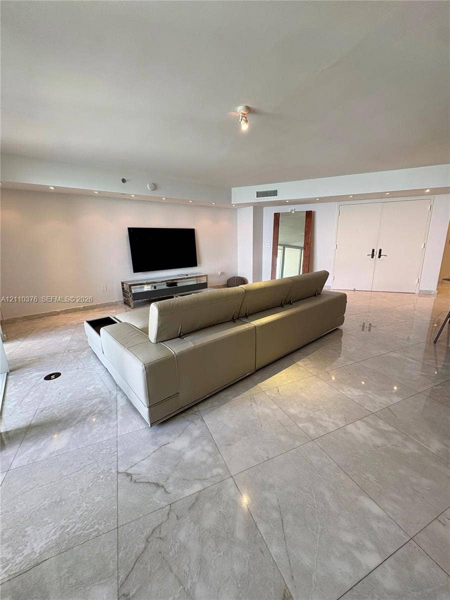Large-format stone tile flooring, recessed cove lighting, and double-entry doors