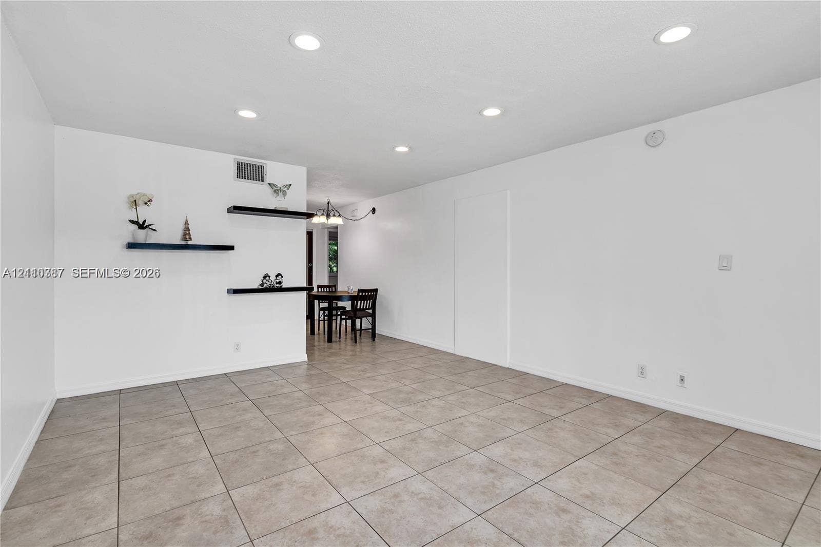 Neutral-toned tile flooring, recessed ceiling lighting, and three built-in wall-mounted display shelves