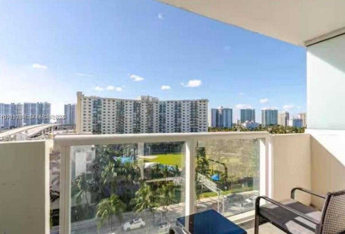 Private balcony featuring glass panel railing and urban skyscape