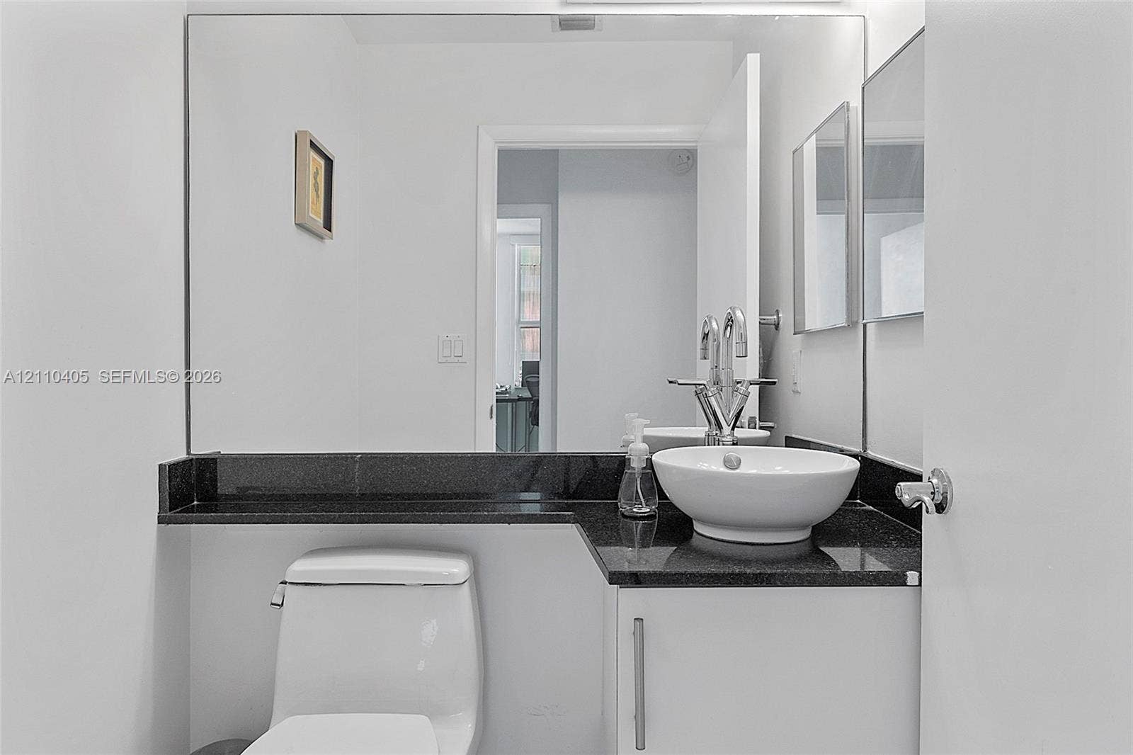 Polished black countertop vanity featuring a white vessel sink, high-arch chrome faucet, and expansive wall-mounted mirror