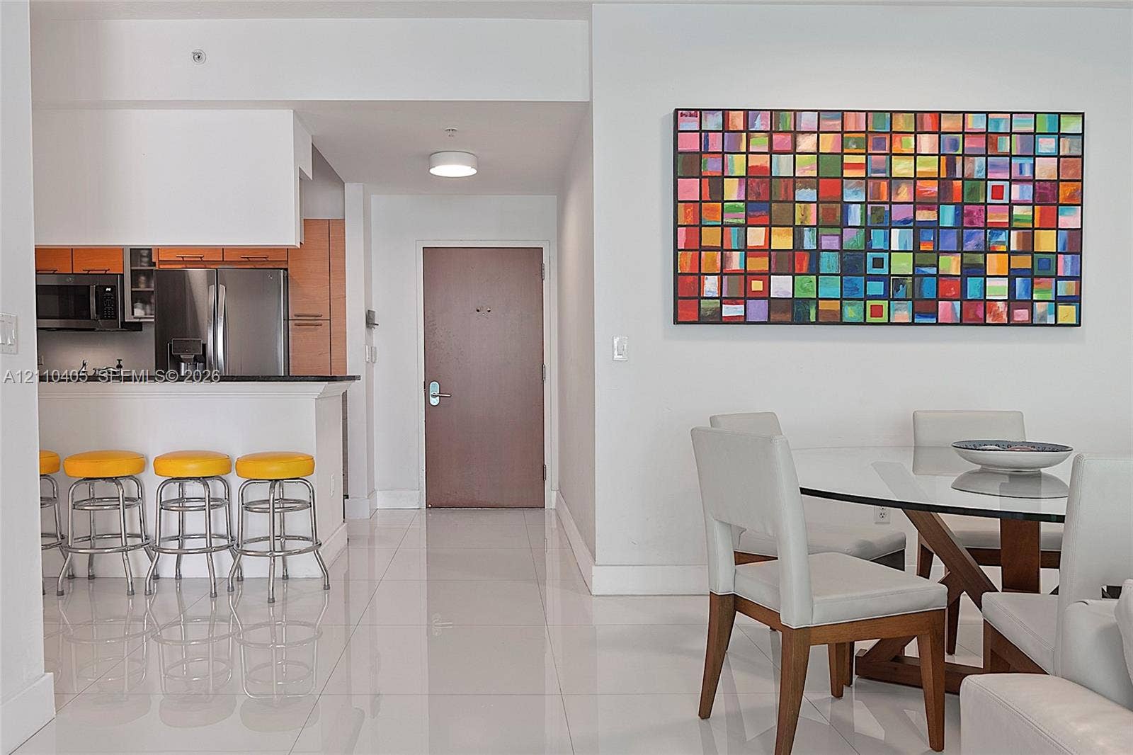 Kitchen featuring a breakfast bar with stone-surfaced countertops, stainless steel appliances, wood-finish cabinetry, and polished tile flooring