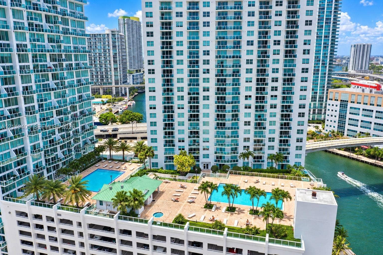 Elevated outdoor deck featuring multiple swimming pools, a spa, paved sunning areas, and mature palm landscaping