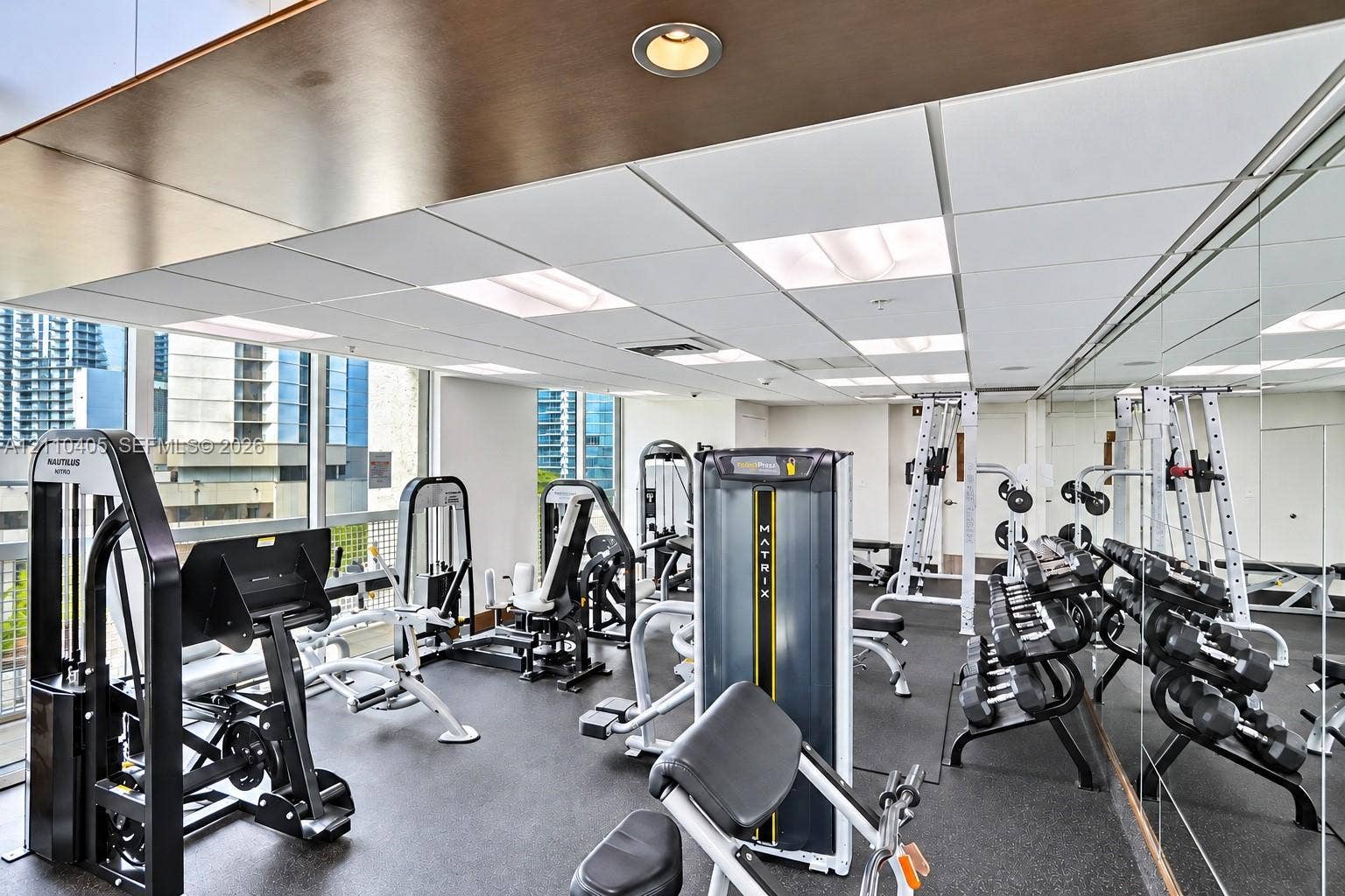 Fitness center featuring floor-to-ceiling windows, rubberized flooring, recessed lighting, and mirrored wall surfaces