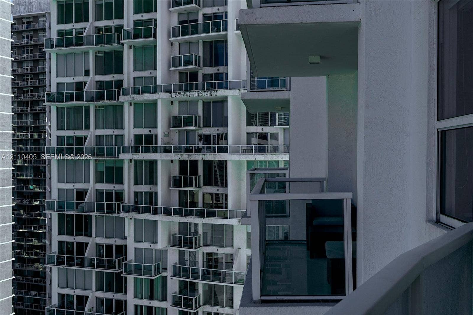 High-rise exterior featuring individual balconies with glass railings and floor-to-ceiling windows