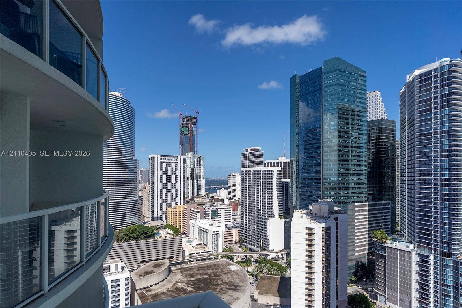 Curved balcony featuring glass railings and expansive city skyline backdrop