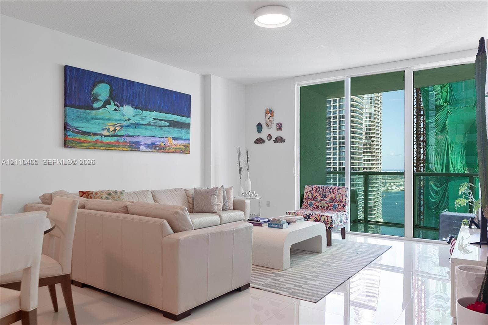 Living area featuring polished tile flooring, floor-to-ceiling glass sliding doors, and a flush-mount ceiling light fixture