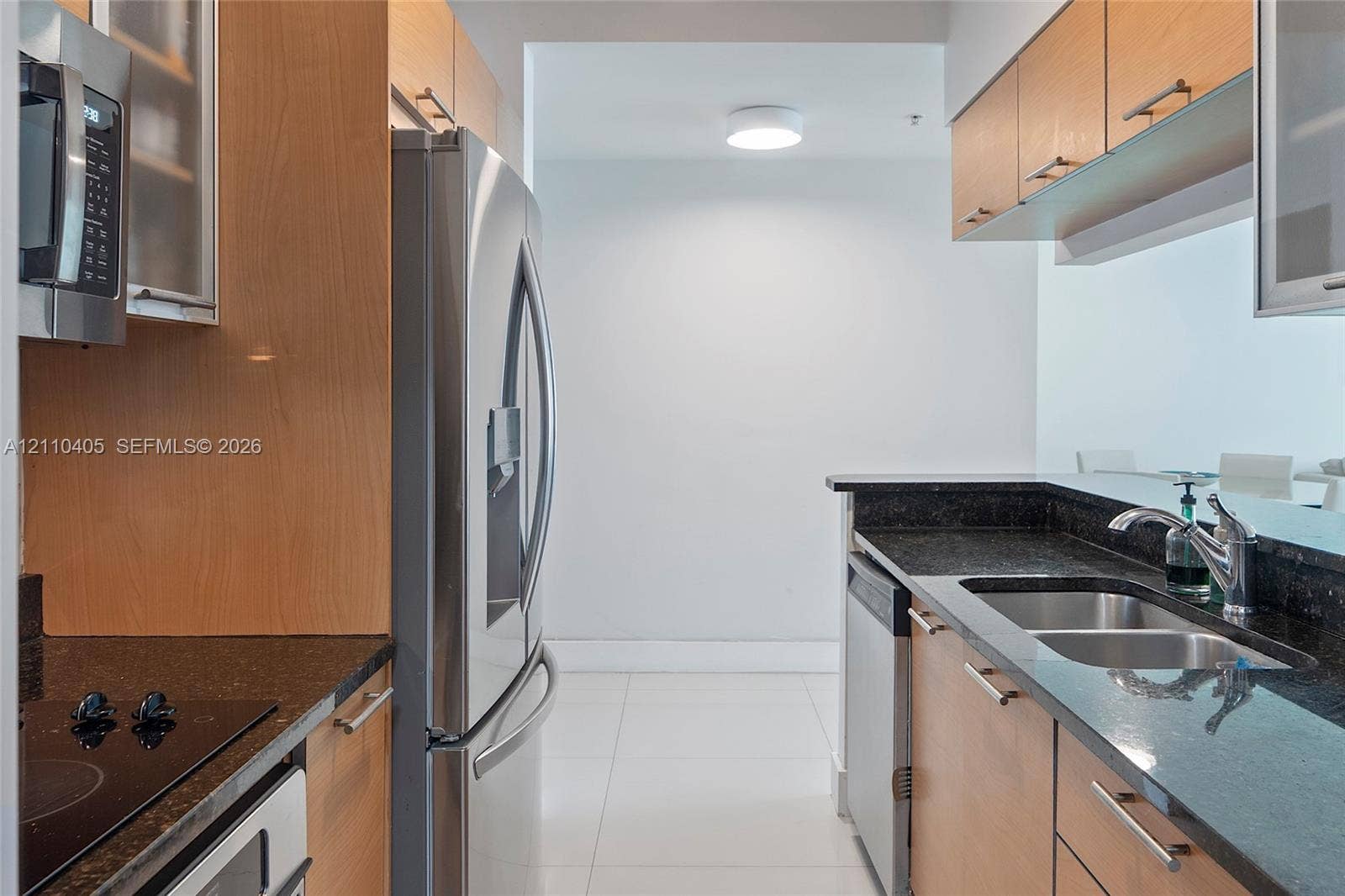 Kitchen featuring wood-veneer cabinetry, stone countertops, stainless steel appliances, and a dual-basin undermount sink