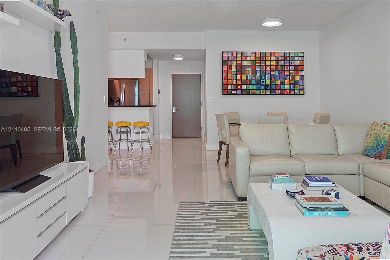 Glossy tile flooring, built-in wall-mounted media console, and kitchen breakfast bar with overhead recessed lighting