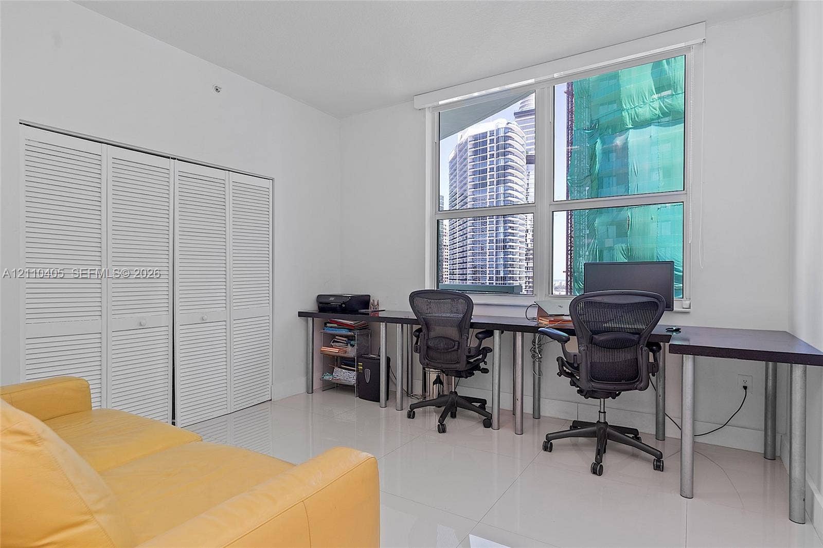 Floor-to-ceiling windows, high-gloss tile flooring, and louvered double-door closet