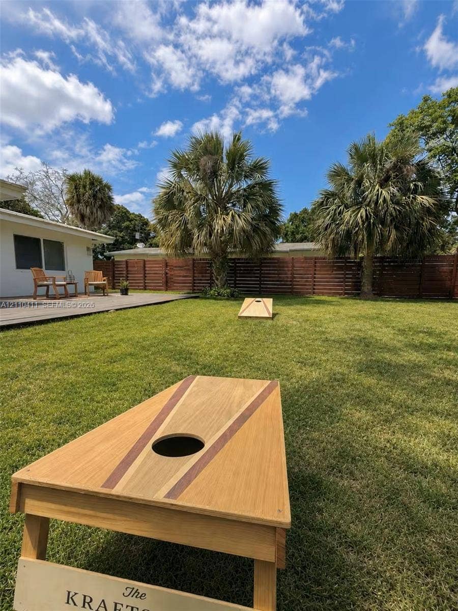 Expansive backyard featuring a leveled grass lawn, wood-finish horizontal privacy fencing, and a raised wooden deck