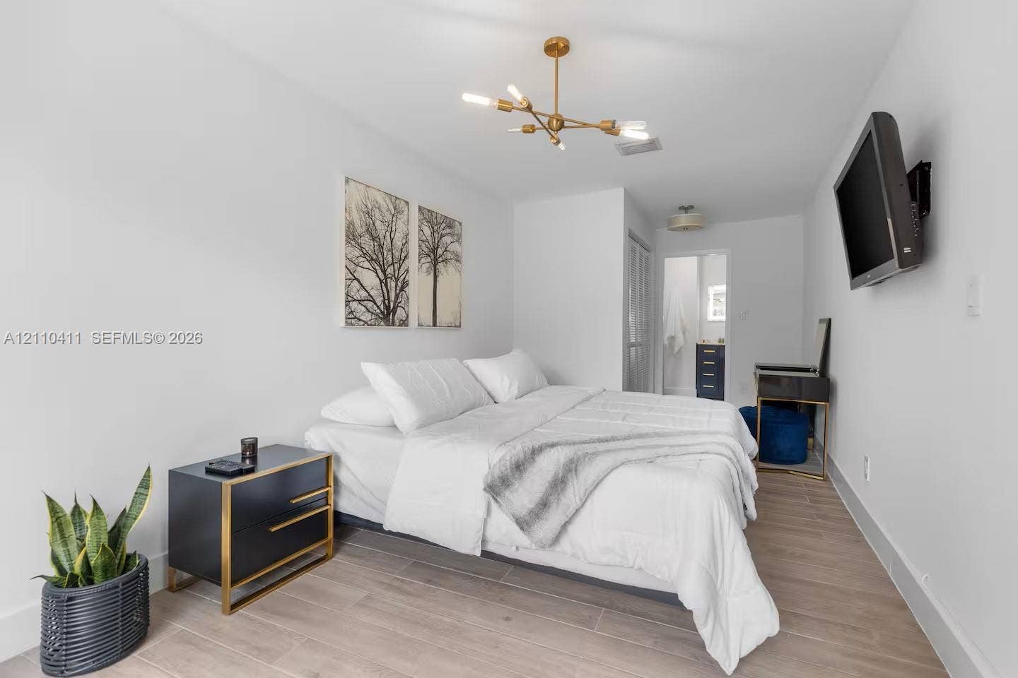 Wood-finish flooring, multi-arm gold-tone chandelier, and neutral wall palette