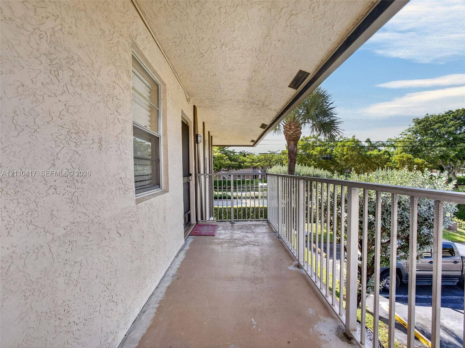 2369 NW 89th Drive, #514, Coral Springs, FL 33065 Covered outdoor balcony featuring textured stucco exterior walls, smooth concrete flooring, and metal railings