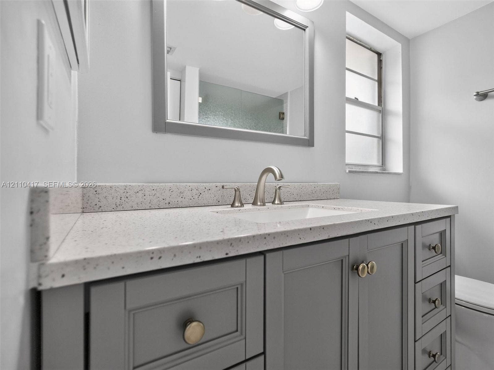 2369 NW 89th Drive, #514, Coral Springs, FL 33065 Grey shaker-style vanity featuring a light-toned speckled countertop, undermount sink, brushed nickel faucet, and integrated mirror