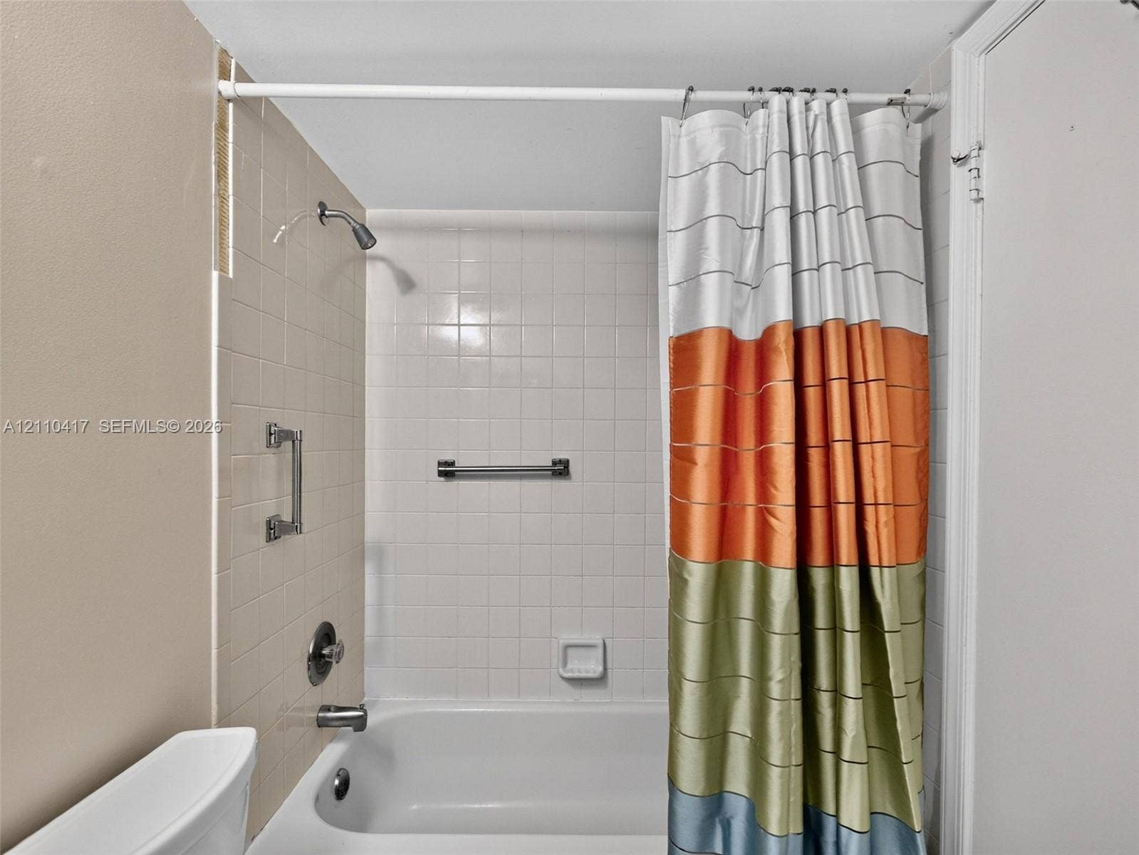 2369 NW 89th Drive, #514, Coral Springs, FL 33065 Bathtub and shower combination featuring a porcelain finish, wall-mounted shower head, integrated grab bar, and neutral square wall tiling