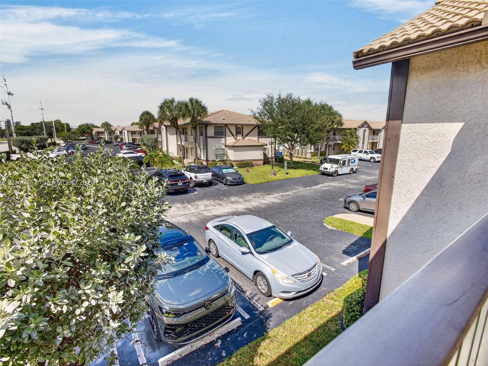 2369 NW 89th Drive, #514, Coral Springs, FL 33065 Exterior view featuring multi-story residential buildings with stucco facades and tile roofing, set within a community landscape of established palm trees and paved parking areas