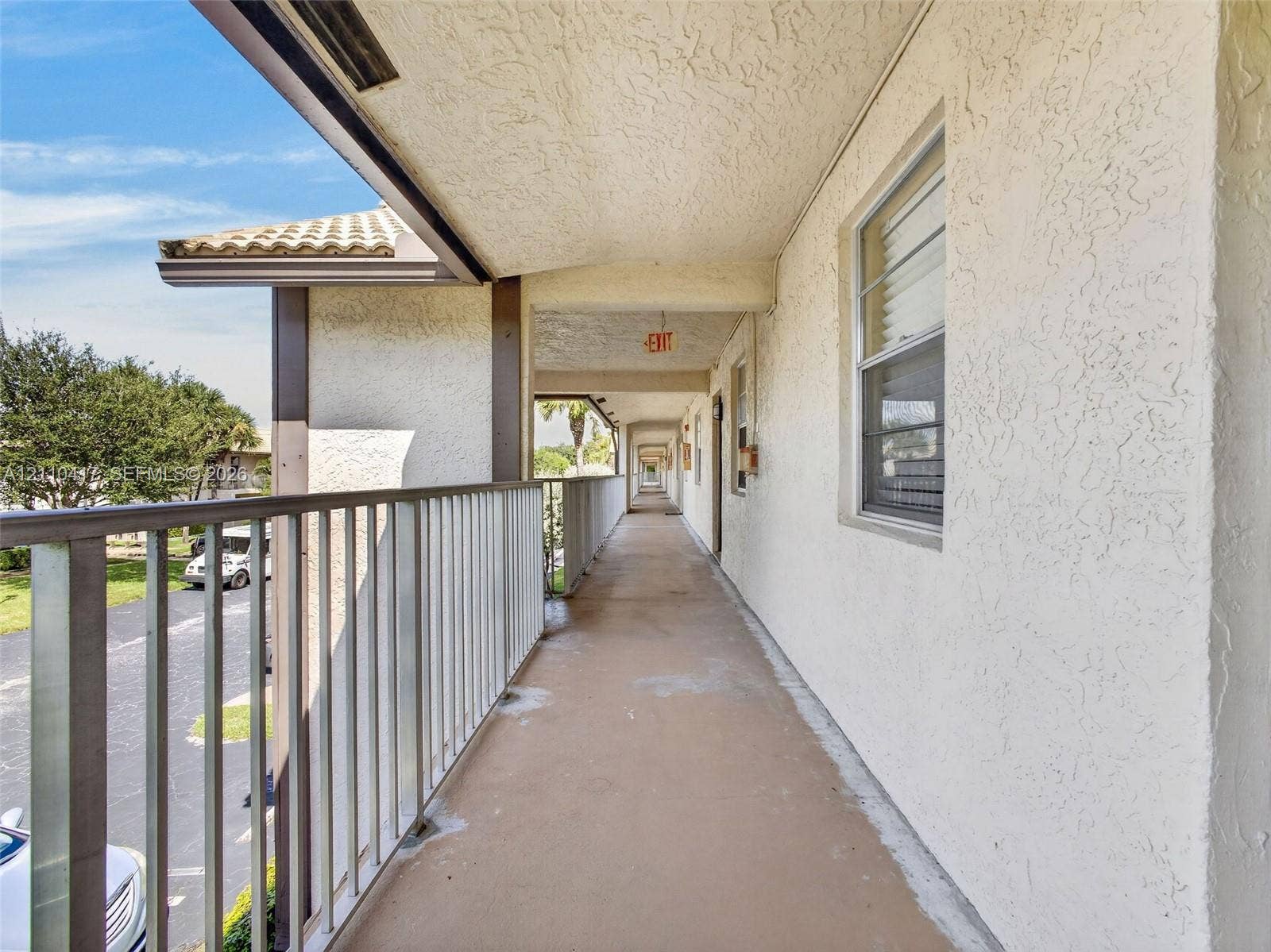 2369 NW 89th Drive, #514, Coral Springs, FL 33065 Covered exterior walkway featuring stucco walls, metal railings, and concrete flooring
