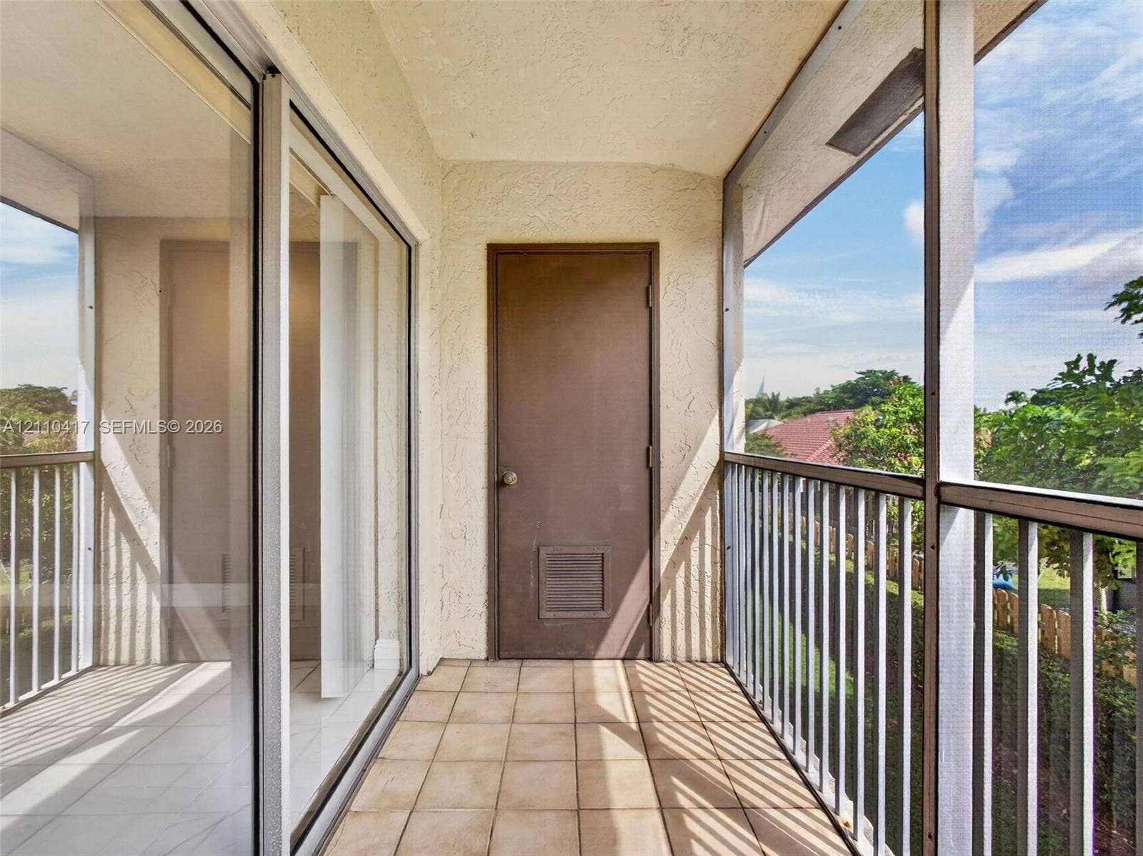 2369 NW 89th Drive, #514, Coral Springs, FL 33065 Covered balcony featuring ceramic tile flooring, a screen enclosure, metal railings, and sliding glass entry doors