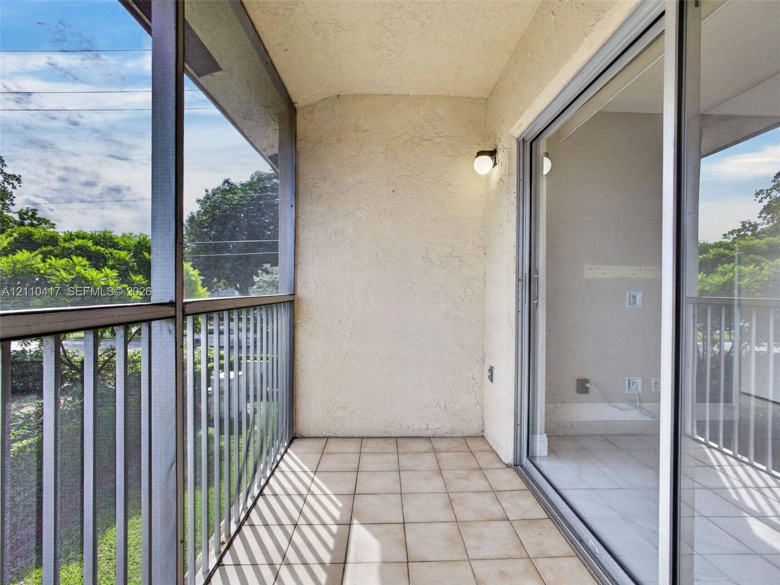 2369 NW 89th Drive, #514, Coral Springs, FL 33065 Screened-in balcony featuring light-toned ceramic tile flooring, a textured stucco wall finish, metal railing, and a sliding glass door
