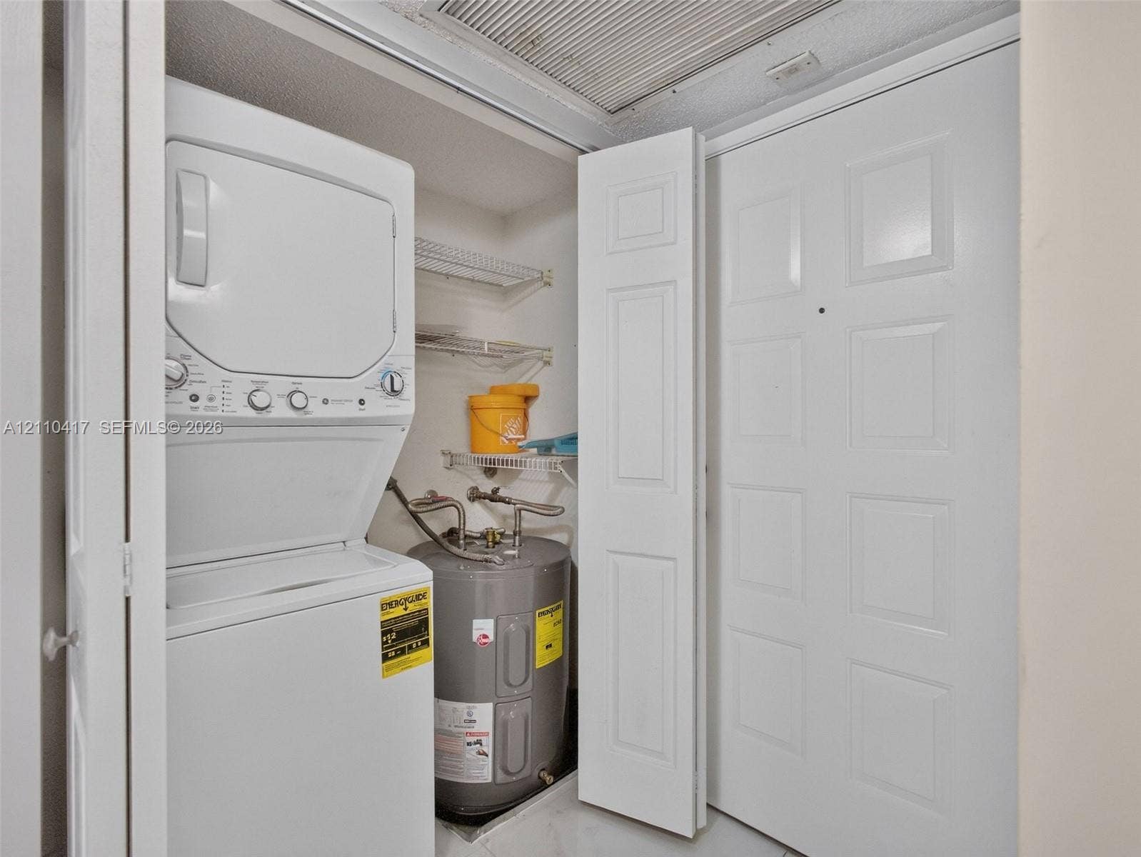 2369 NW 89th Drive, #514, Coral Springs, FL 33065 Utility closet featuring a stacked washer and dryer, integrated electric water heater, and wire shelving