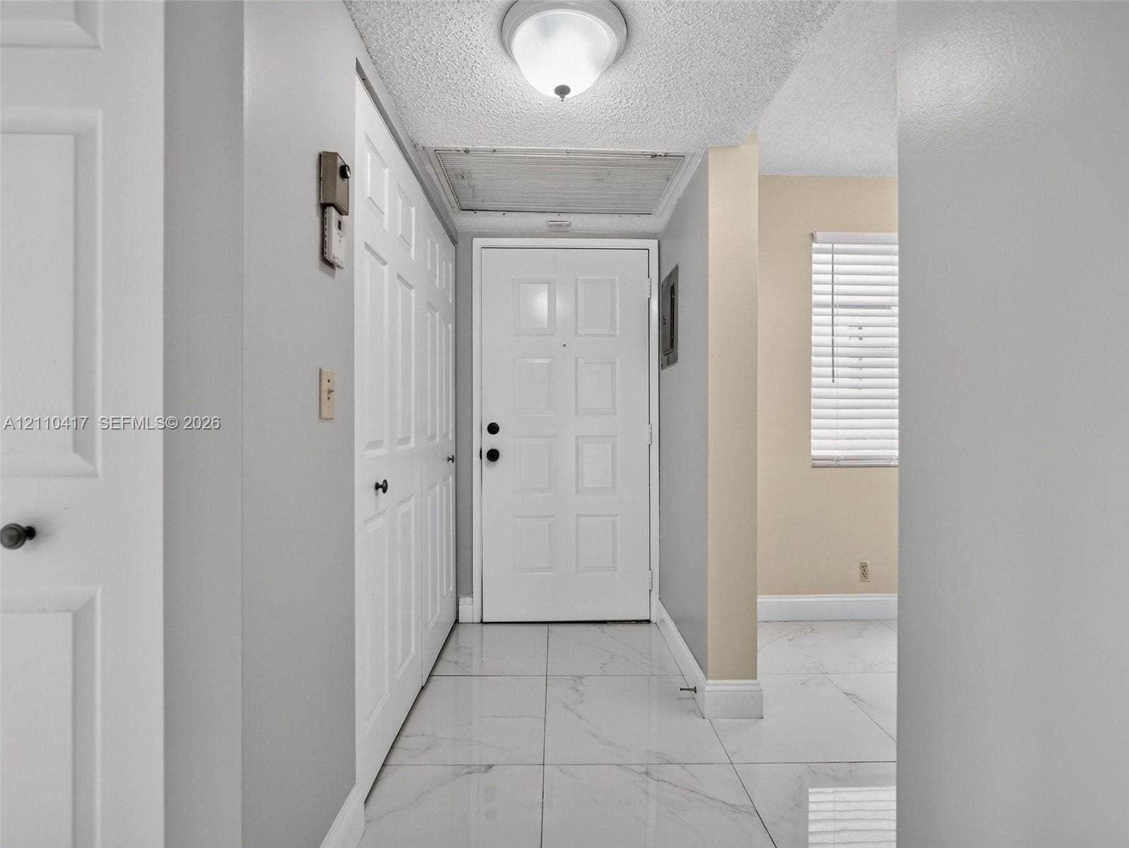 2369 NW 89th Drive, #514, Coral Springs, FL 33065 Entryway featuring large-format white tile flooring, paneled white interior doors, a flush-mount ceiling fixture, and a white paneled exterior door