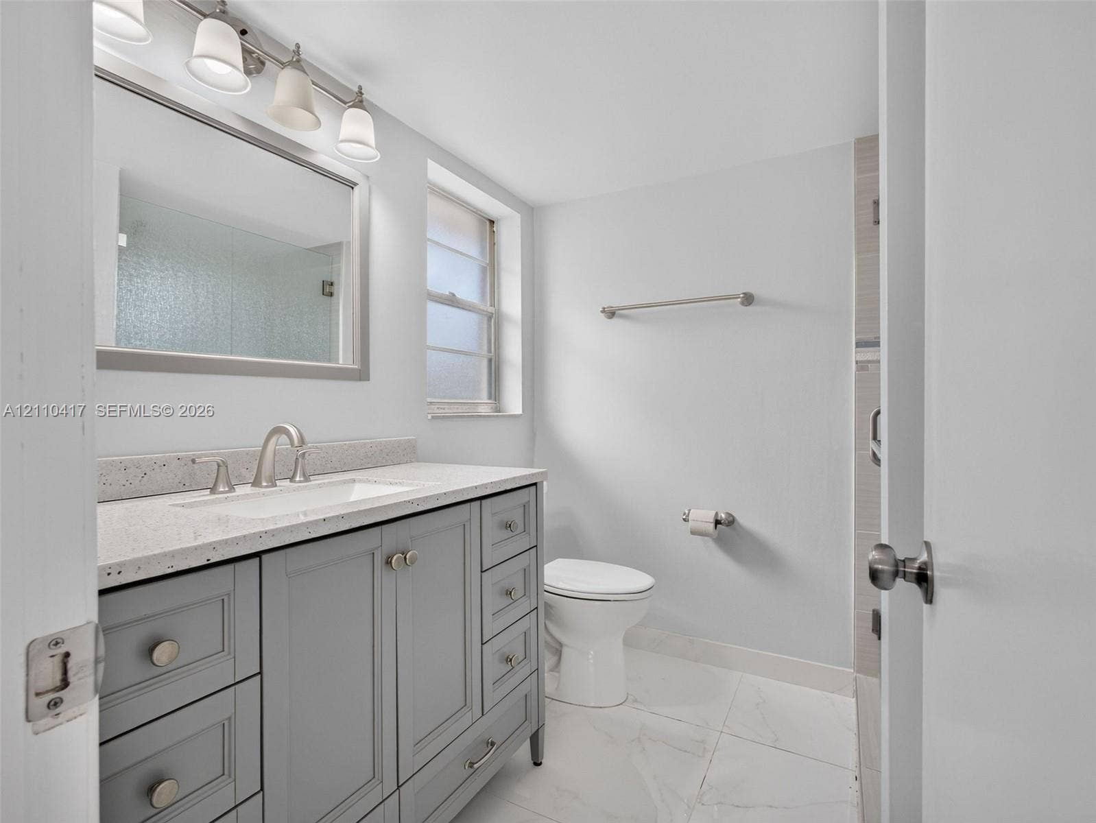 2369 NW 89th Drive, #514, Coral Springs, FL 33065 Bathroom featuring a grey shaker-style vanity, stone-composite countertop with an integrated basin, multi-drawer storage, polished nickel-finish hardware, and large-format porcelain floor tile