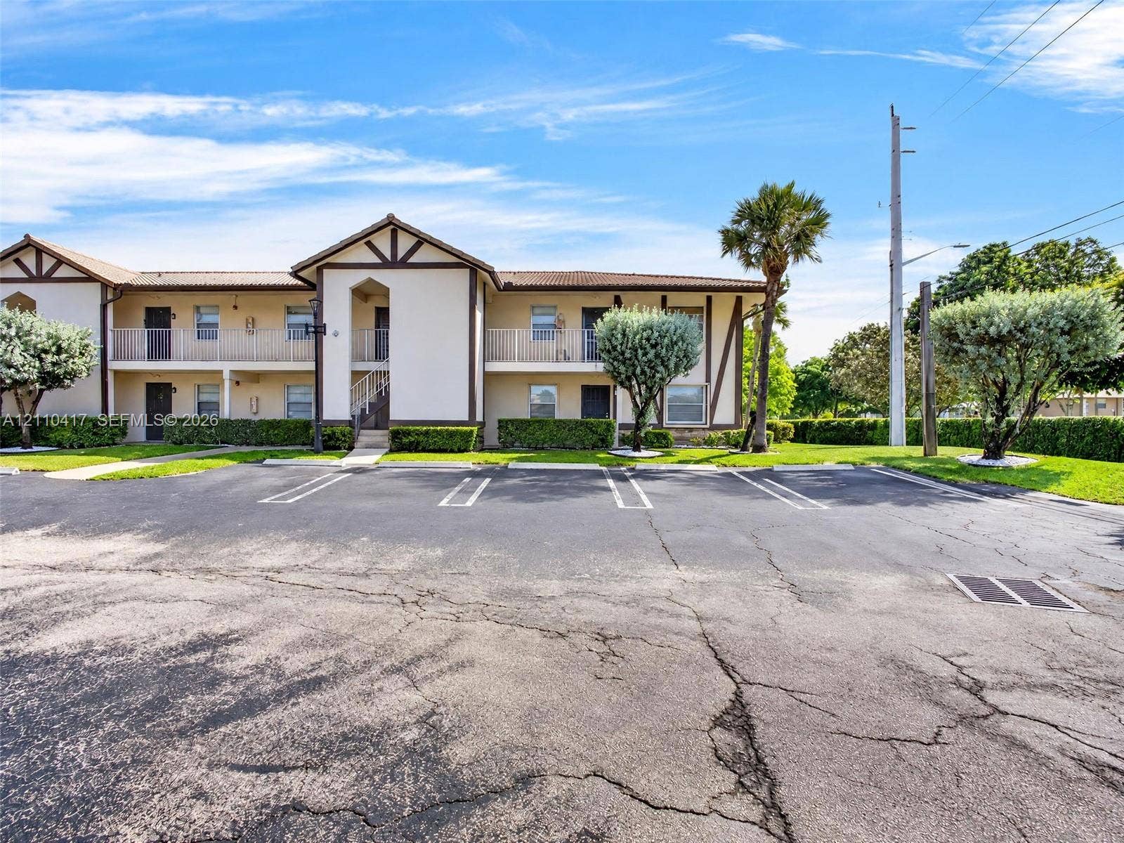 2369 NW 89th Drive, #514, Coral Springs, FL 33065 Two-story stucco exterior featuring timber-framed accents, upper-level railed balconies, covered ground-level entrances, and mature landscaping
