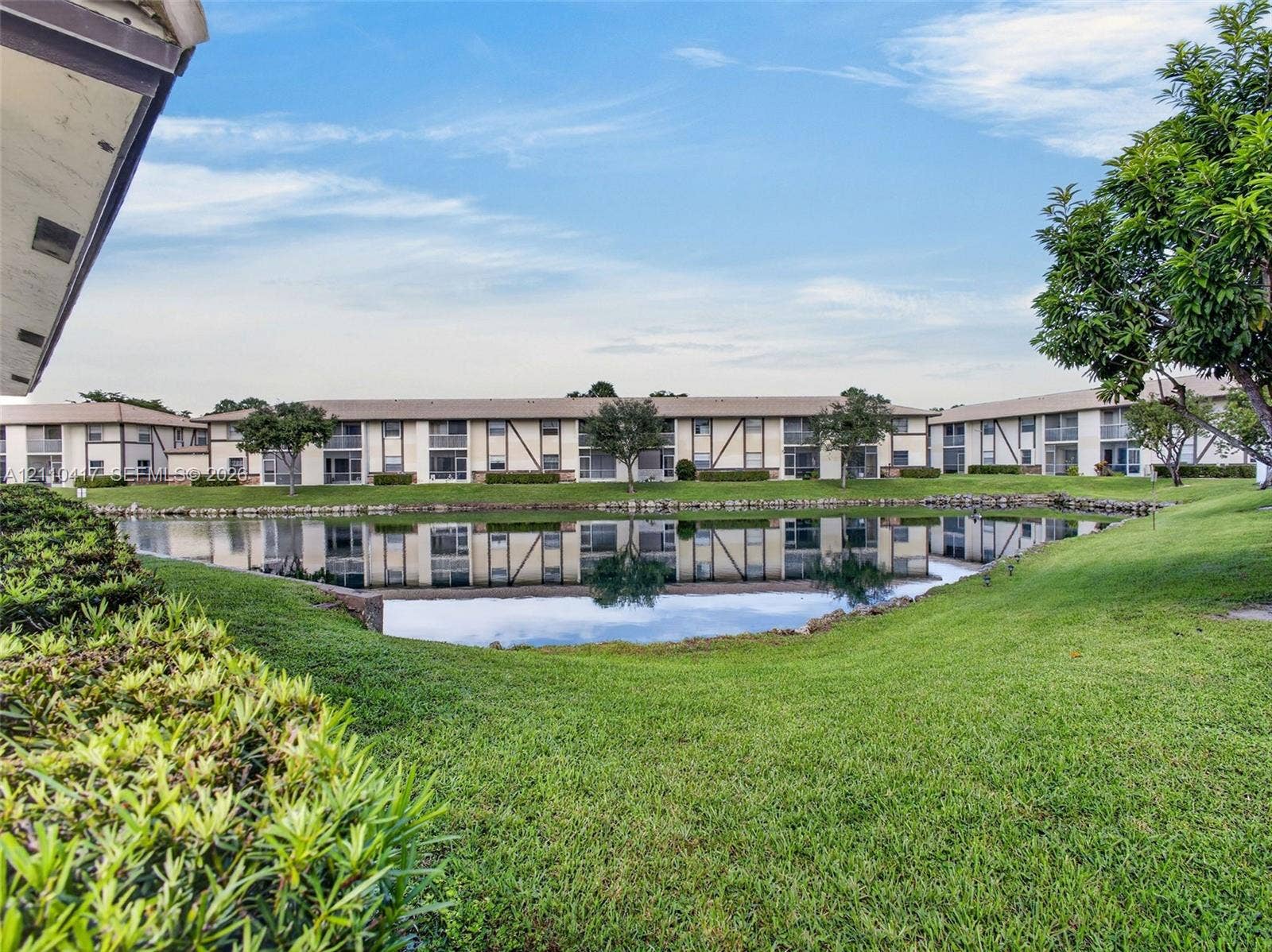2369 NW 89th Drive, #514, Coral Springs, FL 33065 Multi-level exterior with stucco facade featuring a central water feature, stone-lined pond edges, and landscaped green space