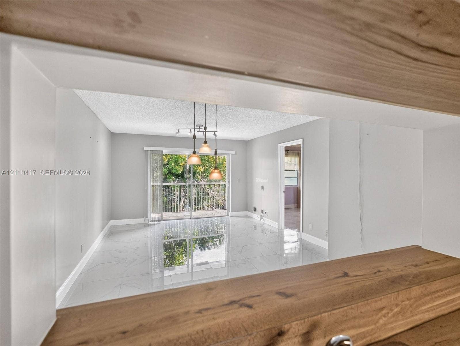 2369 NW 89th Drive, #514, Coral Springs, FL 33065 Polished tile flooring, wood-finish breakfast bar, three-pendant drop lighting, and sliding glass door with balcony access